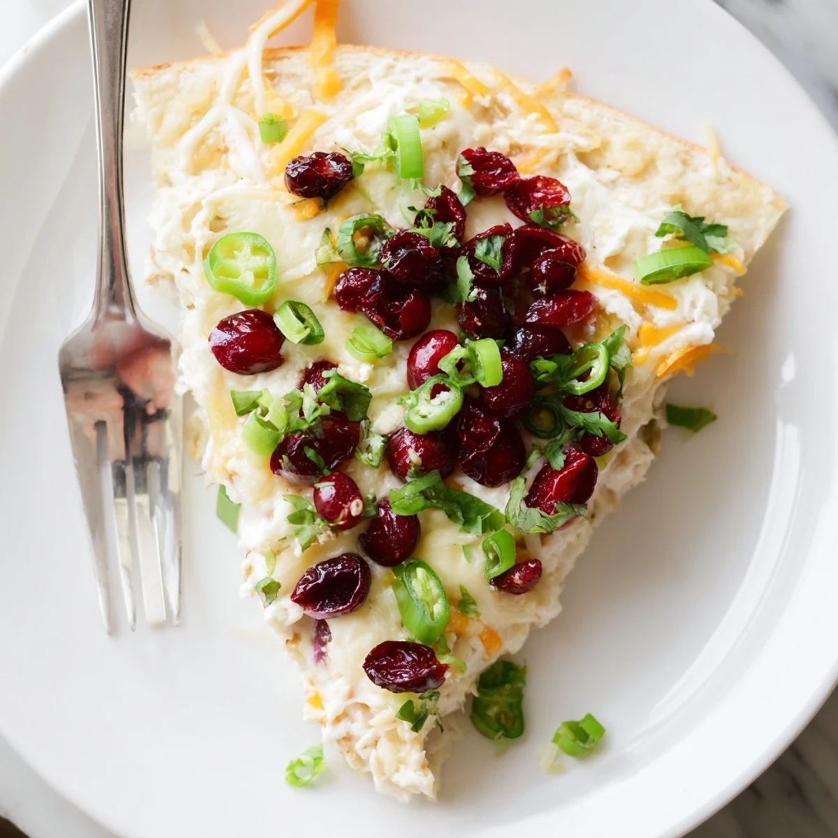 Creamy cranberry jalapeño dip pizza topped with melted cheese and vibrant colors.