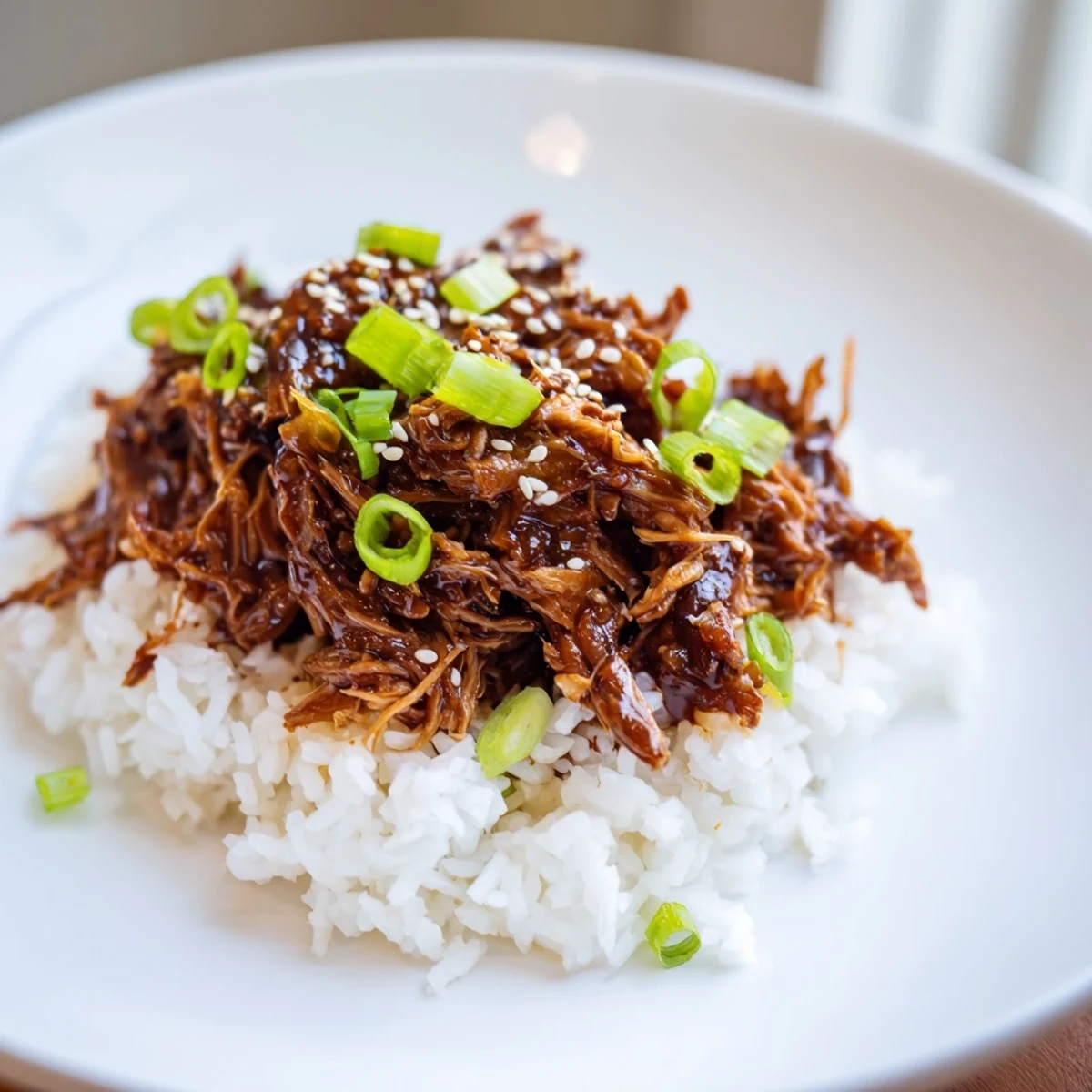 Tender slow cooker teriyaki chicken, coated in sweet sauce, served on fluffy rice; a colorful plate.