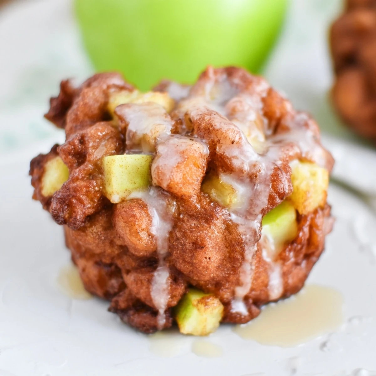 Golden-brown homemade apple fritters, fried to crispy perfection, are drizzled with sweet glaze.