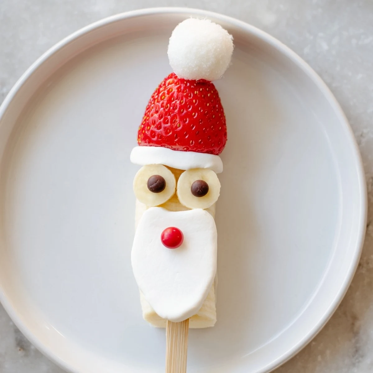 Festive Banana Santa Snack Sticks presented with red berries and whipped cream, ready to eat.