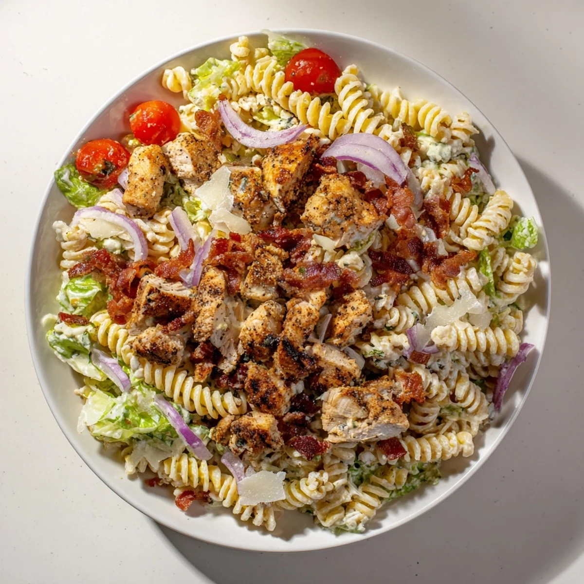 Chicken Caesar Pasta Salad, a creamy delight, features grilled chicken and crispy bacon atop rotini.