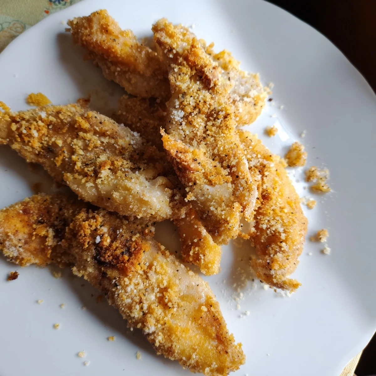 Close-up of air-fried chicken tenders glistening and crunchy, a healthier take on crispy chicken fingers.