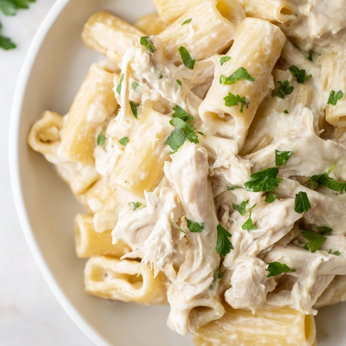 Delicious slow cooker chicken Alfredo pasta bake, topped with melted mozzarella and fresh parsley, steaming hot.