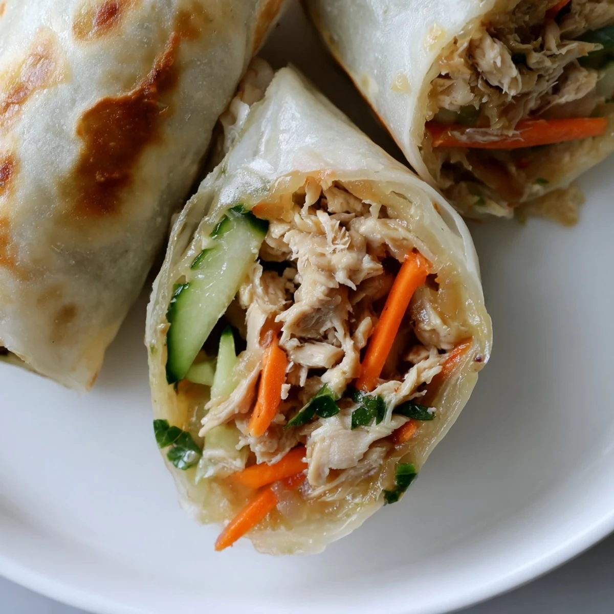 Golden-brown Garlicky Pulled Chicken Wraps feature shredded chicken and crispy rice paper textures.