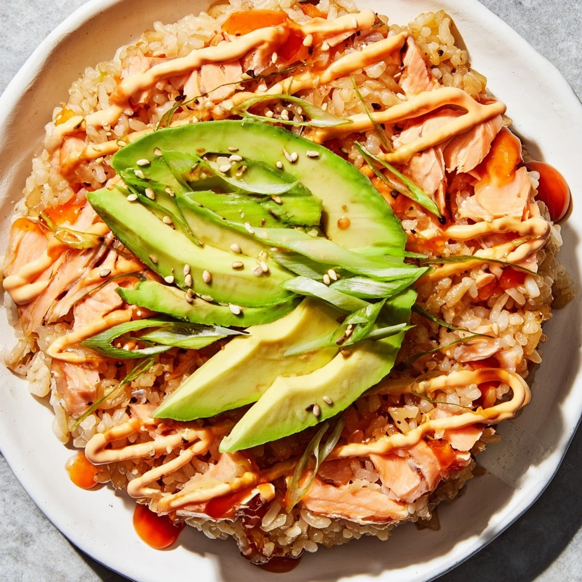 Creamy avocado and toasted sesame seeds top the delicious Emily Mariko Salmon Rice Bowl with crispy seaweed.