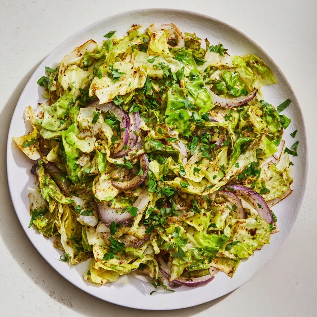 A close-up of sautéed cabbage with garlic and Mediterranean spices, garnished with fresh parsley and lemon wedges for serving.  