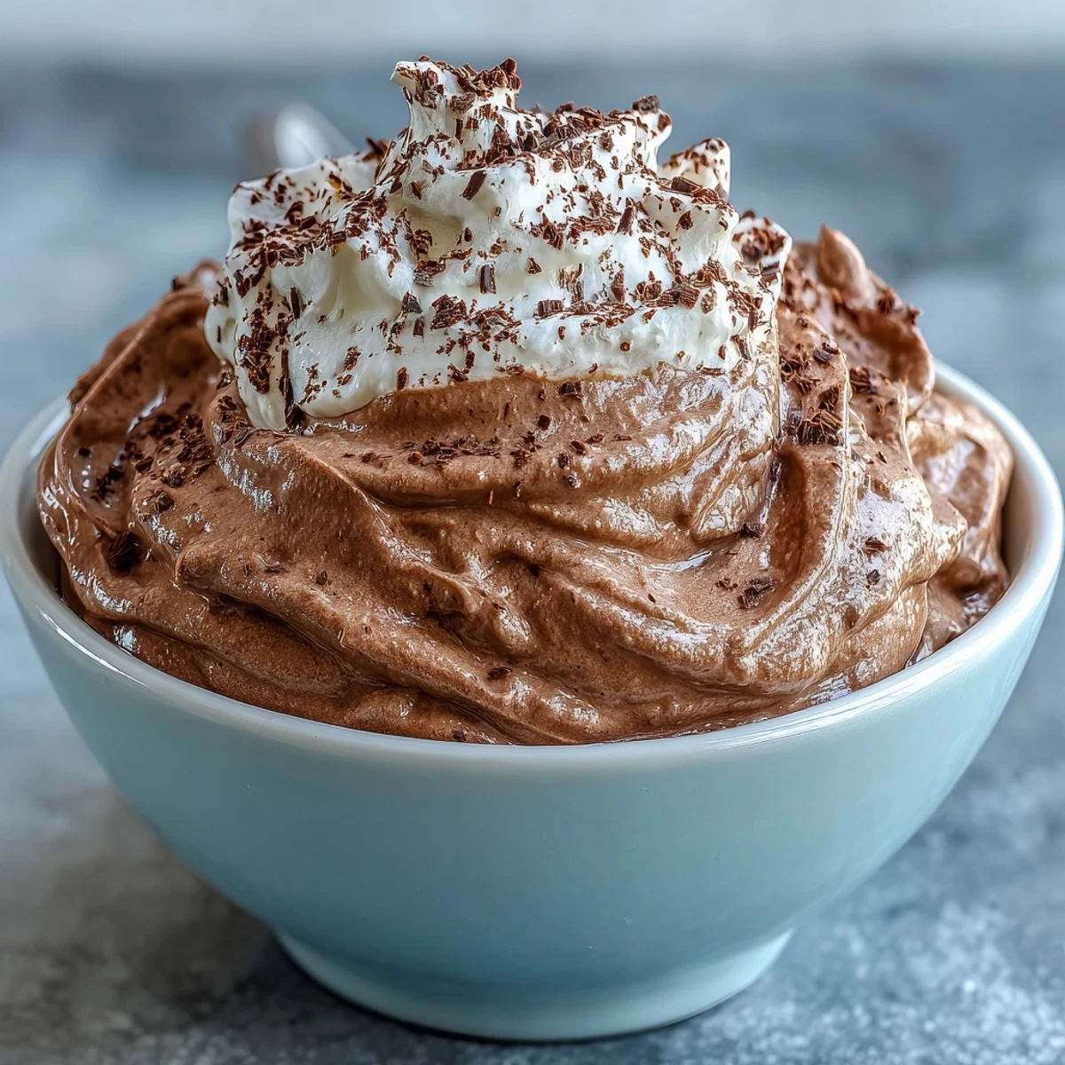 Creamy chocolate protein fluff in a bowl, topped with fresh berries and chocolate chips for a healthy snack.