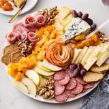 Elegant charcuterie board artfully decorated with apple rosettes and savory meats.