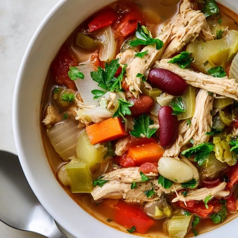 A steaming bowl of Cajun Turkey Veggie Soup garnished with fresh parsley.  