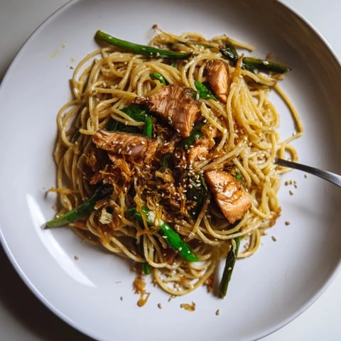 Pan-fried salmon pasta garnished with scallions and sesame seeds, bursting with umami flavors.  