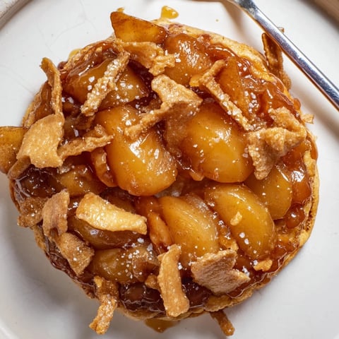 Decadent caramel apple tarte Tatin drizzled with candy crunch for irresistible sweetness.  
