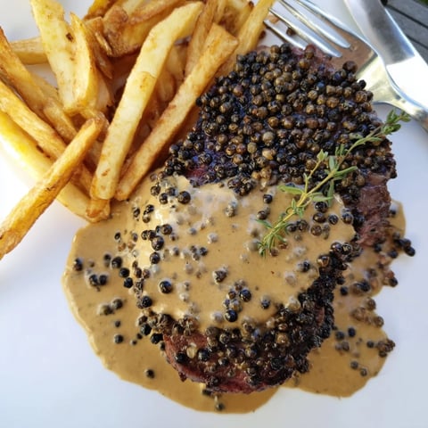 Succulent Classic Peppercorn Ribeye garnished with creamy sauce and crispy fries.  