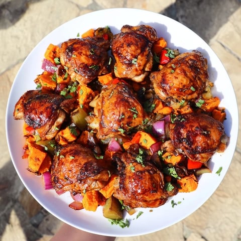 Succulent maple bourbon chicken atop hearty sweet potato hash with vibrant vegetables.  