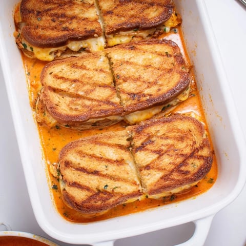 Easy Tomato Soup & Grilled Cheese Casserole Bake bubbling golden brown in a casserole dish.