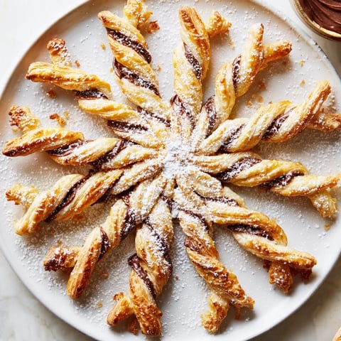 Golden, flaky Express Nutella Puff Pastry Snowflakes, dusted with powdered sugar, ready to be enjoyed as dessert.