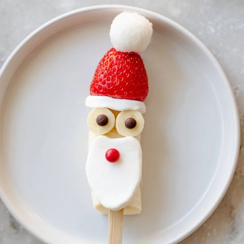 Festive Banana Santa Snack Sticks presented with red berries and whipped cream, ready to eat.
