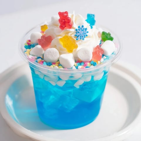 Vibrant snow globe Jello cups, with blue gelatin, marshmallow snow, and festive sprinkles for a fun treat.