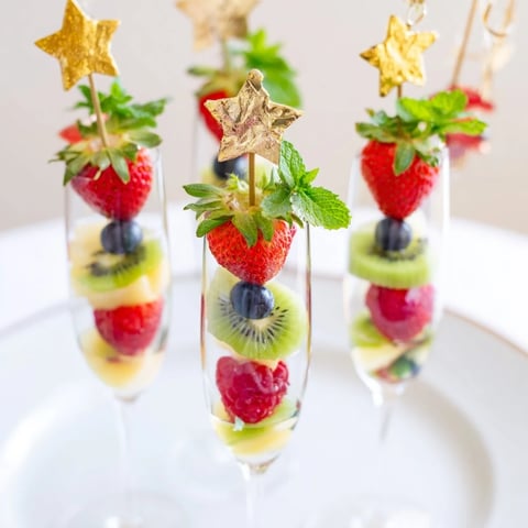 Bright, colorful fruit garnishes over champagne flutes, perfect for a New Year's celebration with vibrant flavors.