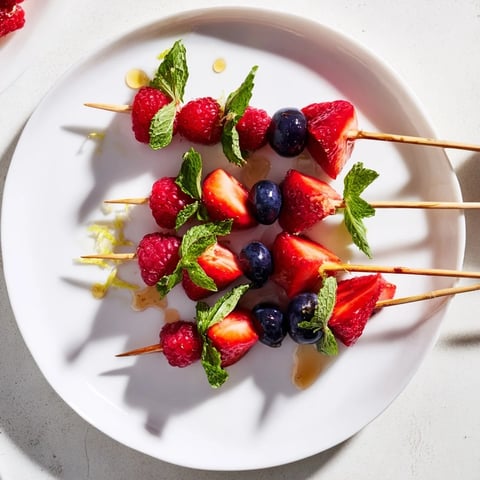 Fresh and colorful fruit skewers featuring plump berries and fragrant mint, ready to enjoy.