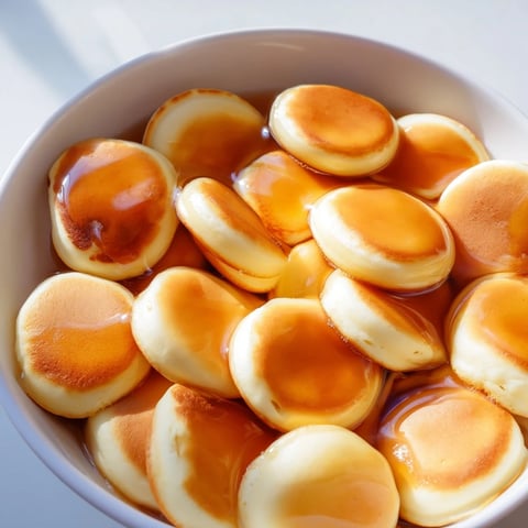 Golden, fluffy pancake cereal swimming in milk, a fun breakfast ready to be enjoyed.