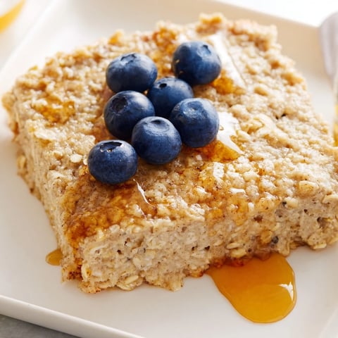 Fluffy baked Protein Pancake Oats, golden brown, served with fresh blueberries and a drizzle.
