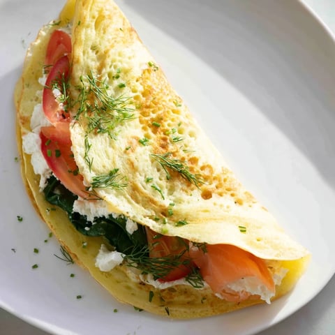 Golden-yellow Blender Egg Crepe Wrap filled with fresh spinach and creamy avocado, ready to eat.