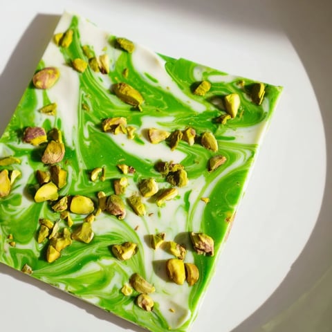 Vibrant Pistachio Matcha White Chocolate bark, swirled and topped with chopped nuts, ready to enjoy.