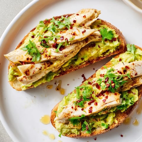 Golden slices of sourdough topped with Smashed Avocado Chicken Toast, drizzled with sweet honey.