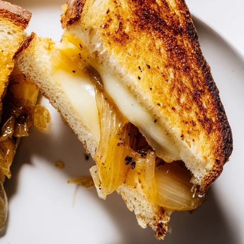 Golden-brown caramelized onion grilled cheese oozes melted cheddar, a comforting American classic, ready to enjoy.