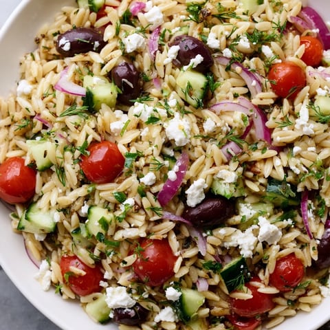 Vibrant Greek orzo salad with juicy tomatoes and creamy feta, ready to enjoy.