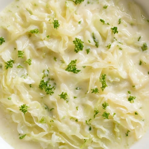 Creamed Cabbage served warm in a white bowl, garnished with fresh parsley, a rich and velvety side dish for weeknight dinners.  