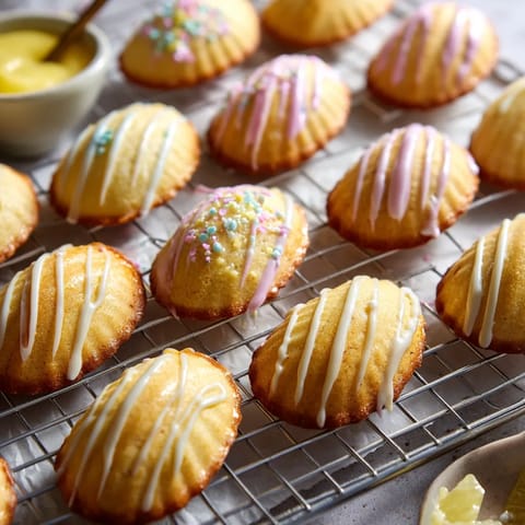 A tray of pastries with white icing and sprinkles.