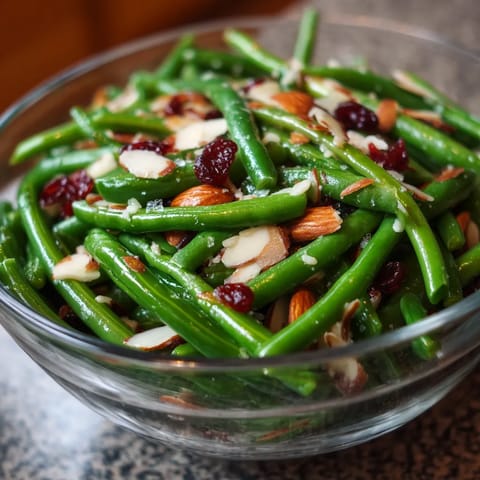 A bowl of green beans with nuts and berries.