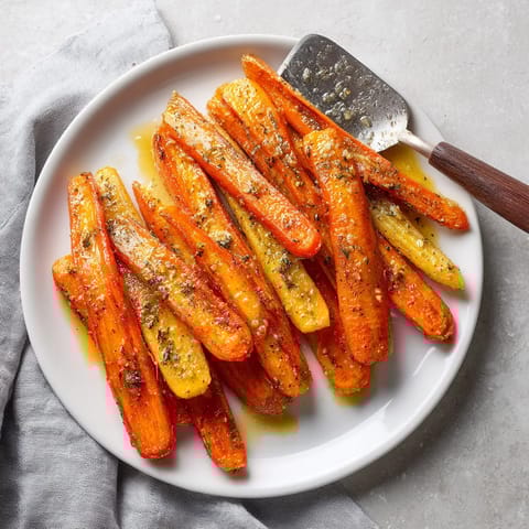 A plate of carrots with a knife on top.