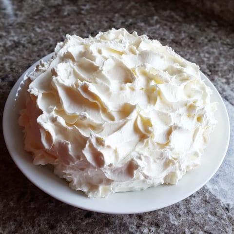 A white cake with whipped cream on a plate.