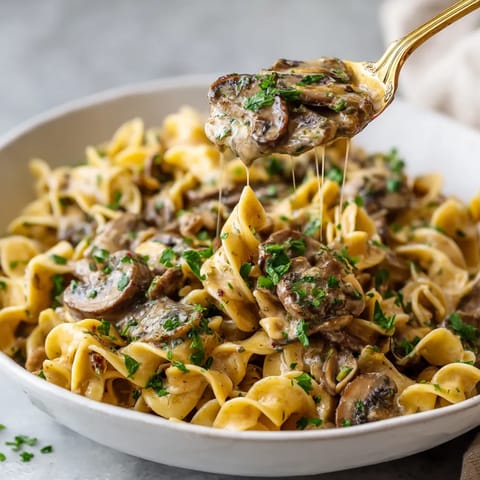 A bowl of pasta with mushrooms and cheese.