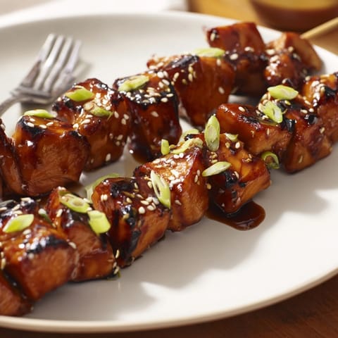 Savory Ginger Teriyaki Chicken Skewers, slightly charred, garnished with sesame and green onion.