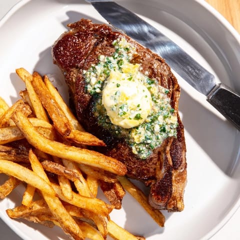 Savory Steakhouse Garlic Butter Steak topped with melting garlic butter next to hot fries.  