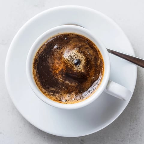 A steaming cup of brewed coffee with rich aroma and creamy foam.  