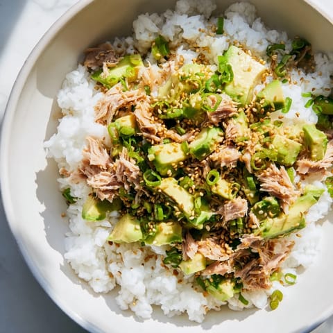Jasmine rice supports a Tuna Avocado Rice Bowl, topped with vibrant avocado and dressing.