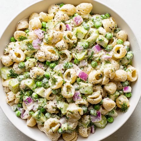 Creamy dill pickle pasta salad: A vibrant view of chilled pasta, pickles, and dressing, perfect for picnics.