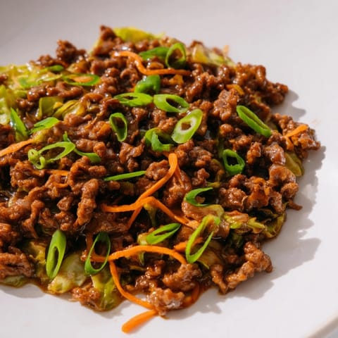 Chinese Ground Beef and Cabbage Stir-Fry sizzling with garlic, ginger, and green onions.  