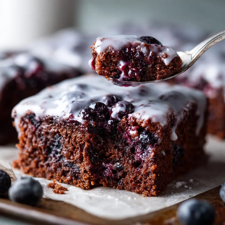 A spoon is scooping up a piece of cake.