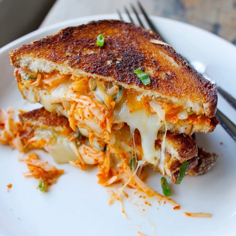 Melting kimchi grilled cheese fusion with tangy Korean flavors, warm sourdough bread crust.