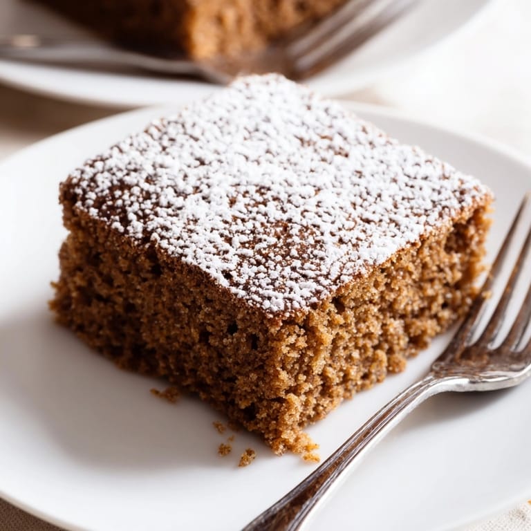 Close-up of a slice of Cinnamon Gingerbread Snack Cake, ready to be served with coffee.
