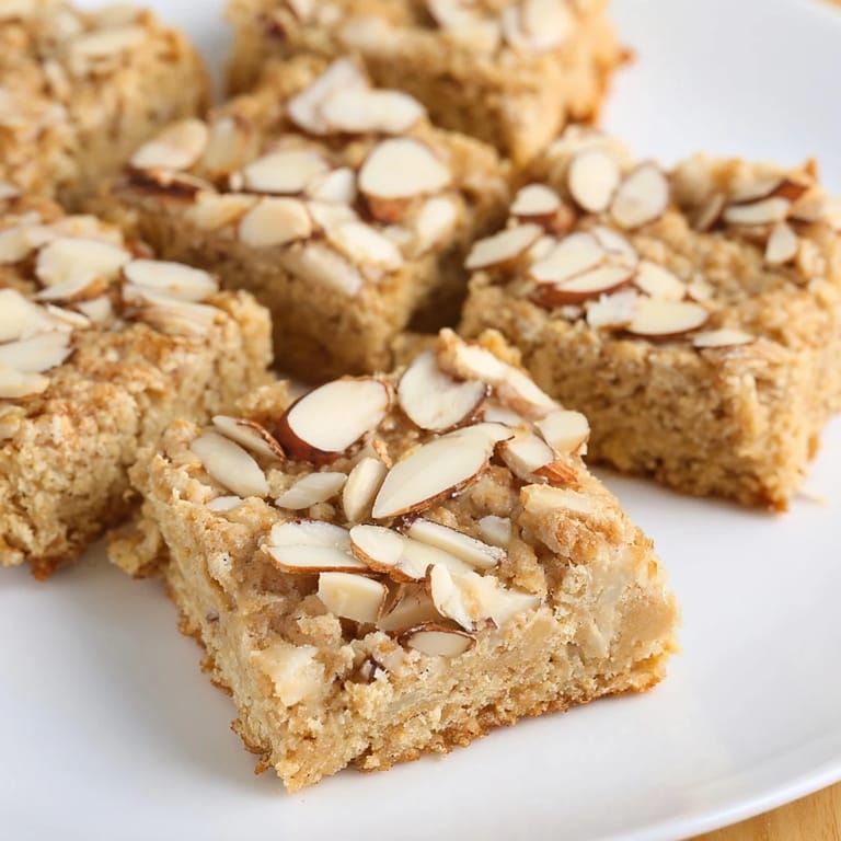 Warm, chewy Protein Cinnamon Almond Squares topped with sliced almonds and cinnamon aroma.