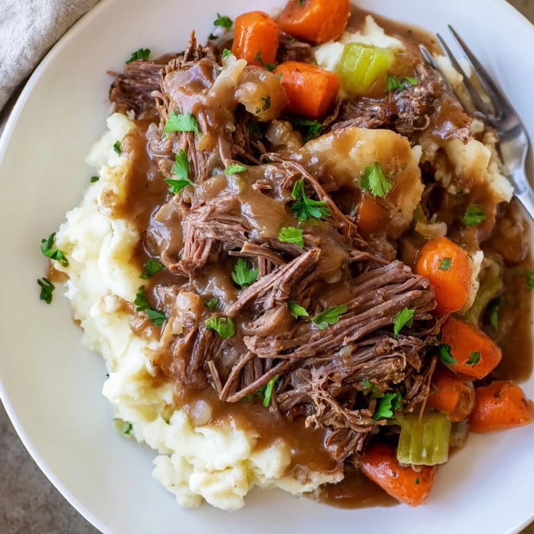 Creamy mashed potatoes complement savory Slow Cooker Pot Roast garnished with fresh parsley.