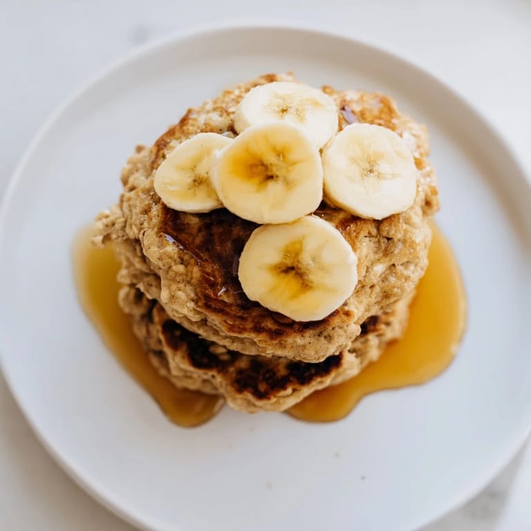 Freshly made, warm banana oat pancakes with visible oats, ready with berries and yogurt.