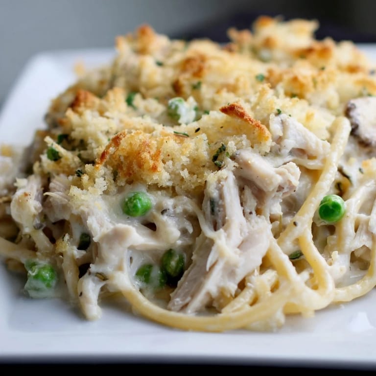 A close-up shot of creamy Turkey/Chicken Tetrazzini, showing tender chicken amidst pasta and peas.