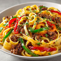A plate of pasta with red peppers and green peppers.